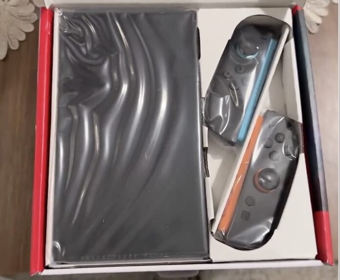 เครื่อง Nintendo Switch 2 ที่ยังอยู่ในบรรจุภัณฑ์ พร้อมจอยคอนสีฟ้าและส้มแบบใหม่ ยังอยู่ในถุงพลาสติกใสภายในกล่อง