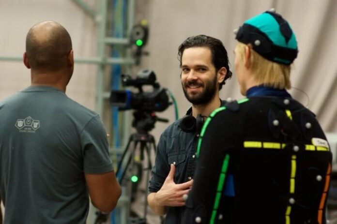 ภาพ Neil Druckmann ผู้บริหารจาก Naughty Dog กำหลังพูดคุยขณะทำงาน