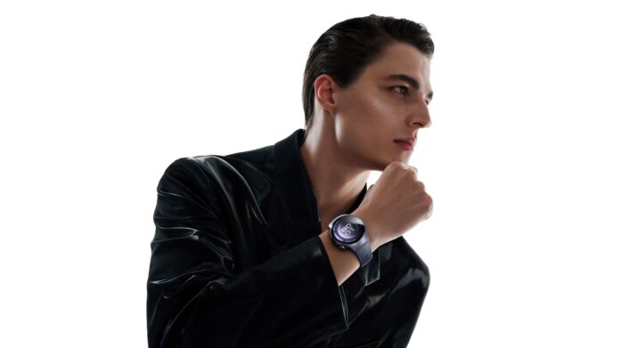 ชายหนุ่มสวมชุดสีดำมันวาว กำลังยกมือขึ้นแตะคาง เผยให้เห็น HUAWEI WATCH 5 บนข้อมือ โดยมีพื้นหลังสีขาวเรียบ