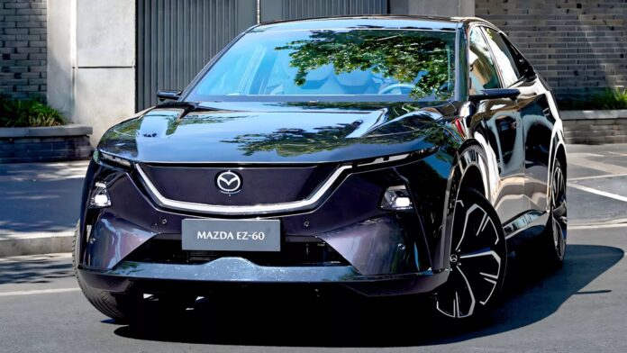 รถยนต์ไฟฟ้า Mazda EZ-60 สีดำมันวาวจอดอยู่ริมถนนหน้าบ้านสมัยใหม่ โดดเด่นด้วยไฟหน้า LED ทรงเฉียบ