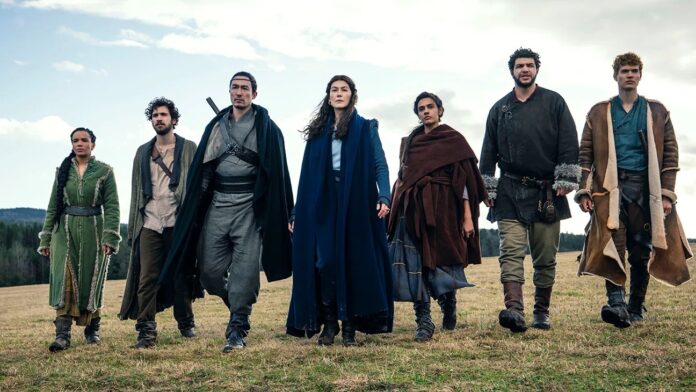 กลุ่มตัวละครหลักจากซีรีส์ The Wheel of Time ยืนเรียงแถวเดินมุ่งหน้าไปข้างหน้าในทุ่งหญ้า