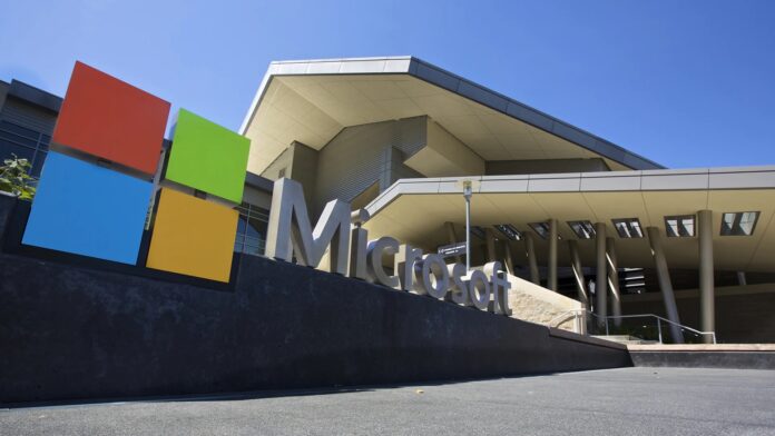 ภาพด้านหน้าสำนักงานใหญ่ของ Microsoft พร้อมโลโก้สีสันสดใสที่ตั้งอยู่หน้าอาคารทรงทันสมัย ภายใต้ท้องฟ้าสดใส