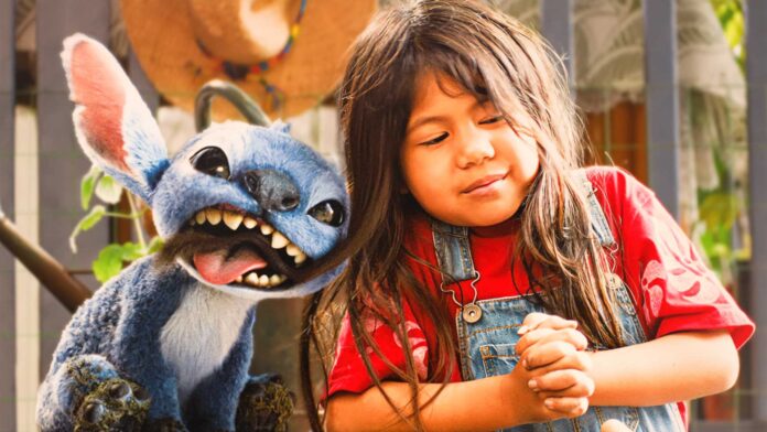 Lilo ในชุดเอี๊ยมยีนส์และเสื้อยืดแดงยืนยิ้มข้าง Stitch สิ่งมีชีวิตต่างดาวขนฟ้าฟันแหลมที่กำลังแลบลิ้น