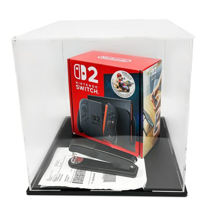 กล่องบรรจุภัณฑ์ Nintendo Switch 2 วางอยู่ในกล่องใสโชว์สินค้า มีแม็กซ์เย็บกระดาษและเอกสารกำกับอยู่ด้านล่าง