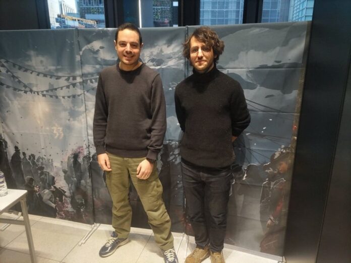 Guillaume Broche ยืนถ่ายรูปที่ด้านหน้าแบนเนอร์ขนาดใหญ่มืดครึ้มในโทนสีเทา