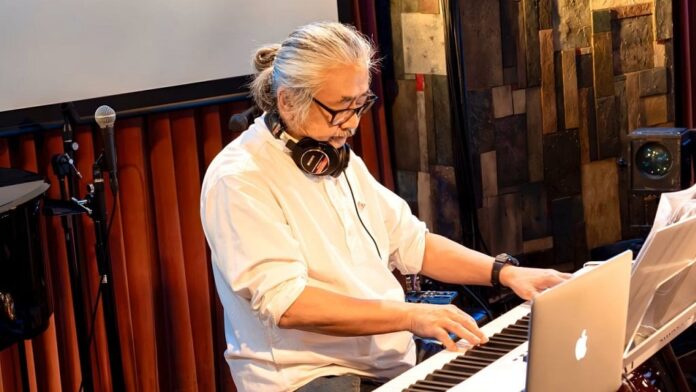 ภาพของ Nobuo Uematsu กำลังแต่งเพลงโดยใช้เปียโน