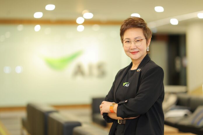 ภาพผู้บริหาร AIS ยืนยิ้มอย่างมั่นใจในออฟฟิศ พร้อมโลโก้ AIS ด้านหลัง