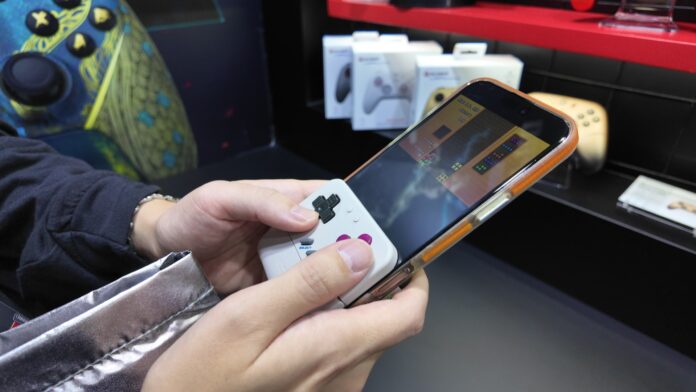 ภาพจอยมือถือสไตล์ Game Boy จาก GameSir สีขาวประกอบเข้ากับสมาร์ทโฟน และมีมือจับอยู่