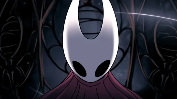 ภาพ Hornet จากเกม Hollow Knight: Silksong ในฉากมืดสลัว ฉากหลังมีโครงสร้างลวดลายคล้ายรังแมลง