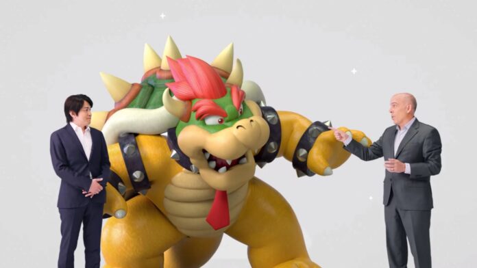 ผู้บริหาร Nintendo ยืนข้าง Bowser ตัวละครจาก Mario ที่ใส่เนคไทสีแดง กำลังยกมือชี้ ขณะนำเสนอใน Nintendo Direct