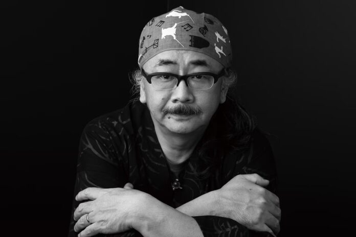 ภาพ Nobuo Uematsu กำลังกอดอกด้วยสีหน้าเรียบเฉย