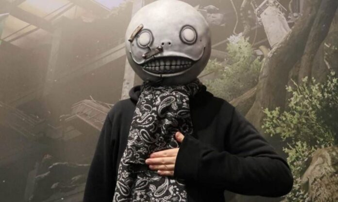 ภาพ Yoko Taro ใส่หมวกมาสคอสส่งยิ้มเอามือทาบอก