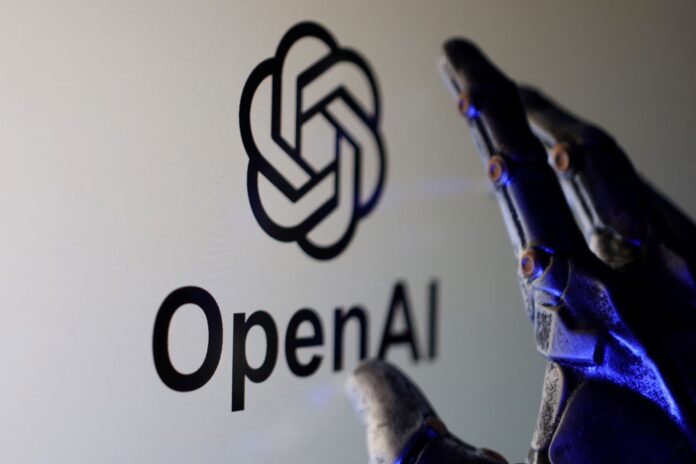 มือหุ่นยนต์กำลังเอื้อมไปยังโลโก้ OpenAI บนพื้นหลังสีขาว โดยมีแสงไฟสีฟ้าสะท้อนบนชิ้นส่วนโลหะของมือ