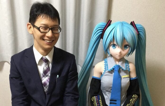 Akihiko Kondo ชายญี่ปุ่นที่แต่งงานกับโฮโลแกรมของ Hatsune Miku นั่งถ่ายภาพคู่กับหุ่นจำลองของภรรยาเสมือน