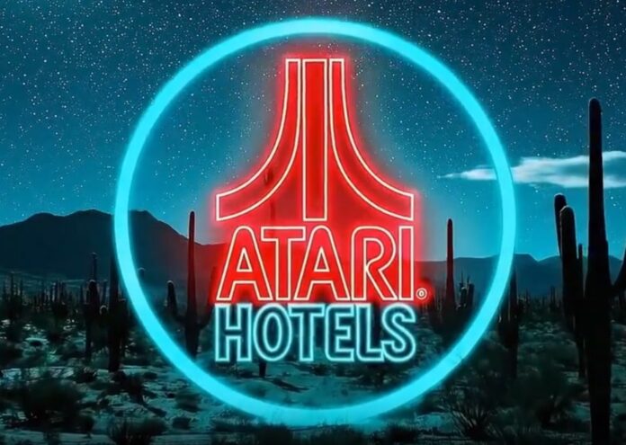 โลโก้ Atari Hotels เรืองแสงสไตล์นีออนกลางทะเลทราย สื่อถึงโครงการ Gaming Hotel ธีมไซเบอร์พังก์ในรัฐแอริโซนา