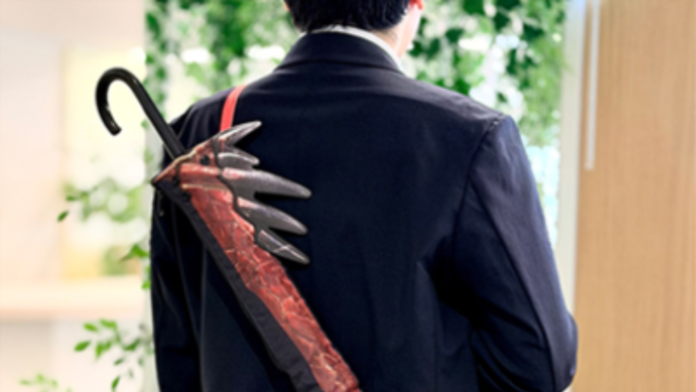 พนักงานออฟฟิศสวมสูทกำลังสะพายปลอกใส่ร่มยาวดีไซน์ดาบคาตานะ จาก Monster Hunter Wilds Rain Theme ให้ลุคเหมือนพกอาวุธนักล่าบนแผ่นหลัง