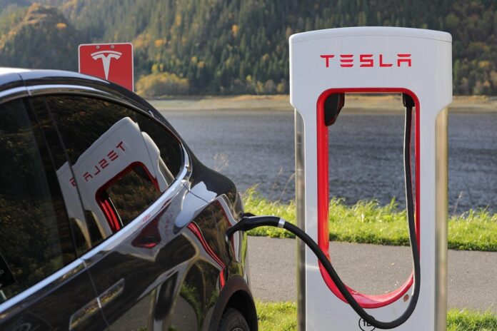 รถ Tesla กำลังชาร์จไฟที่สถานี Supercharger ริมทะเลสาบ