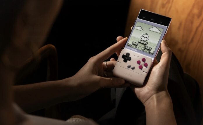 ผู้ใช้งานถือสมาร์ตโฟนที่ติดตั้งคอนโทรลเลอร์ GameSir Pocket Taco สำหรับเล่นเกมเรโทรในโหมดแนวตั้ง สไตล์ Game Boy