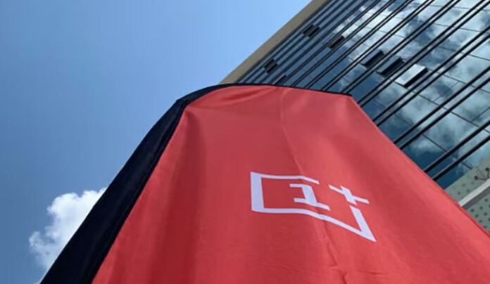 ป้ายโลโก้ OnePlus สีแดงหน้าร้าน บนอาคารสมัยใหม่ มุมมองจากด้านล่าง