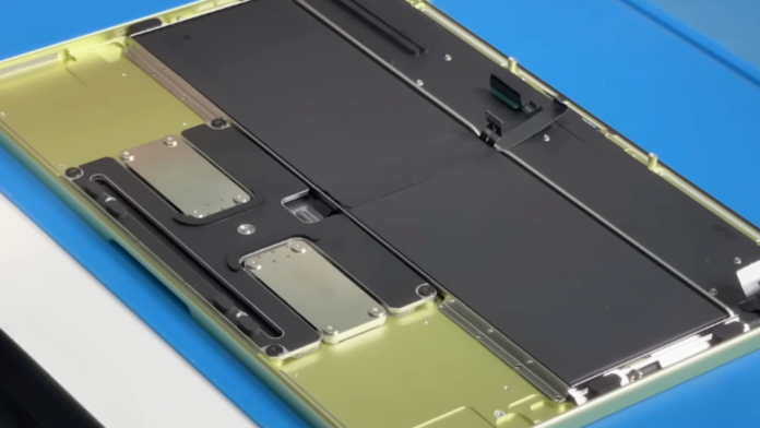 ภายใน MacBook Neo หลังแกะเครื่อง แสดงแบตเตอรี่และโครงสร้างที่ยึดด้วยสกรู ไม่มีการใช้กาว