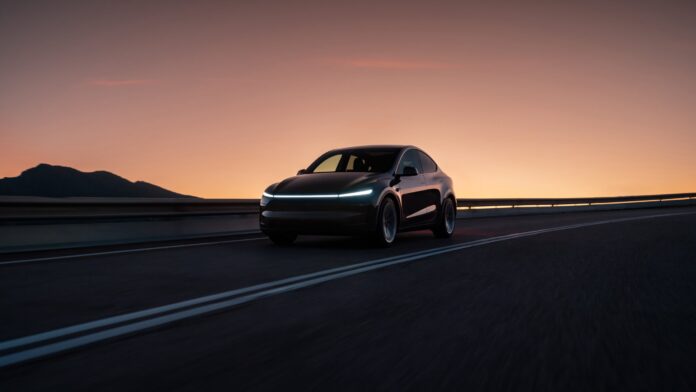 รถ Tesla Model Y วิ่งบนถนนยามพระอาทิตย์ตก พร้อมไฟหน้า LED แบบเส้นยาวโดดเด่น