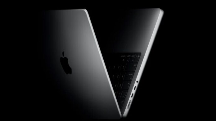 MacBook ถูกเปิดฝาเล็กน้อยบนพื้นหลังสีดำ มองเห็นโลโก้ Apple