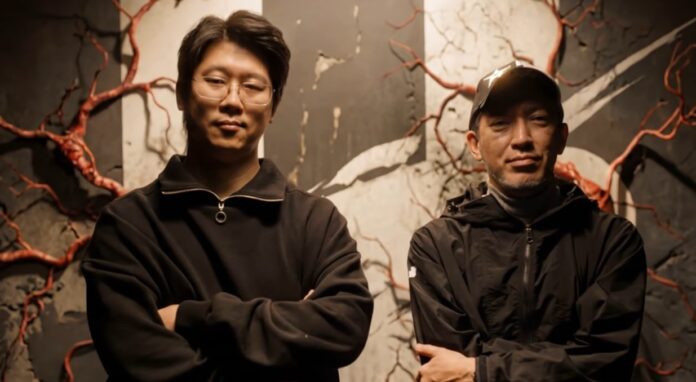 Hyung-tae Kim และ Shinji Mikami ยืนถ่ายภาพร่วมกันหน้าฉากโทนดาร์ก