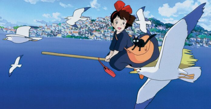 ภาพตัวละครจาก Kiki’s Delivery Service ขี่ไม้กวาดกลางอากาศพร้อมแมวดำ Jiji และนกบินรอบตัว