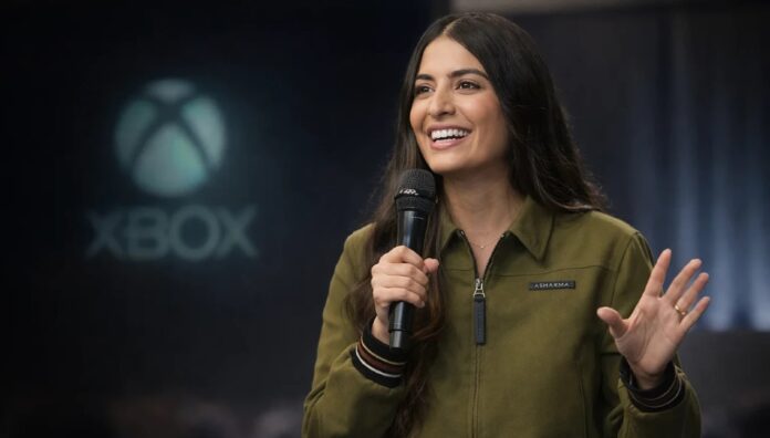 Asha Sharma ซีโอโอของ Xbox กำลังถือไมโครโฟนพูดบนเวที โดยมีโลโก้ Xbox ปรากฏอยู่ด้านหลัง