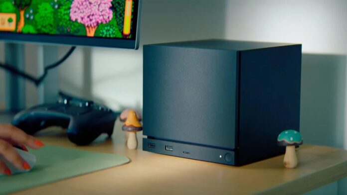 เครื่อง Steam Machine สีดำวางอยู่บนโต๊ะใกล้จอมอนิเตอร์