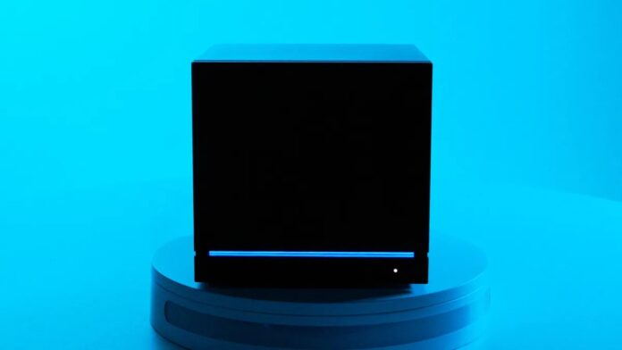 ภาพ Steam Machine สีดำวางบนแท่น พื้นหลังสีฟ้าอ่อน