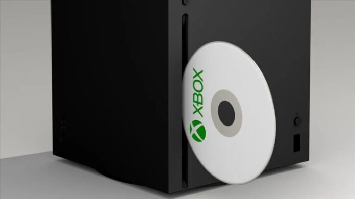 เครื่อง Xbox สีดำพร้อมแผ่นเกมสีขาวกำลังใส่เข้าไปใน Drive ด้านหน้าคอนโซล