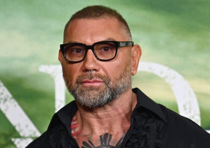 Dave Bautista สวมแว่นกรอบดำและเสื้อเชิ้ตสีดำ กำลังโพสถ่ายภาพในงานอีเวนต์