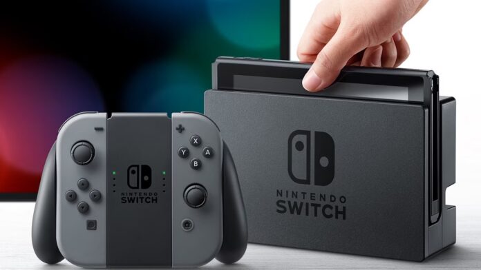 มือคนกำลังจับเครื่อง Nintendo Switch สีเทาดำ