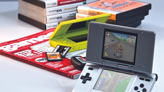 Nintendo DS สีเทาเปิดเครื่องแสดงเกม Mario Kart DS วางคู่กับ Nintendo DS Lite สีเขียว และตลับเกม