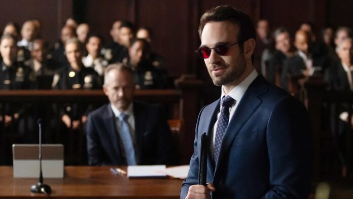 Matt Murdock ในชุดสูทและแว่นตากันแดดสีแดง ในห้องพิจารณาคดี