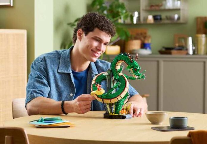 ชายหนุ่มกำลังจัดแสดงโมเดลตัวต่อ LEGO Dragon Ball ชุดเทพเจ้ามังกรเชนรอนและมินิฟิกเกอร์โกคู