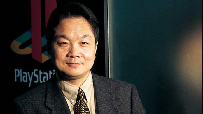 Ken Kutaragi ยืนหน้าฉากหลังโลโก้ PlayStation