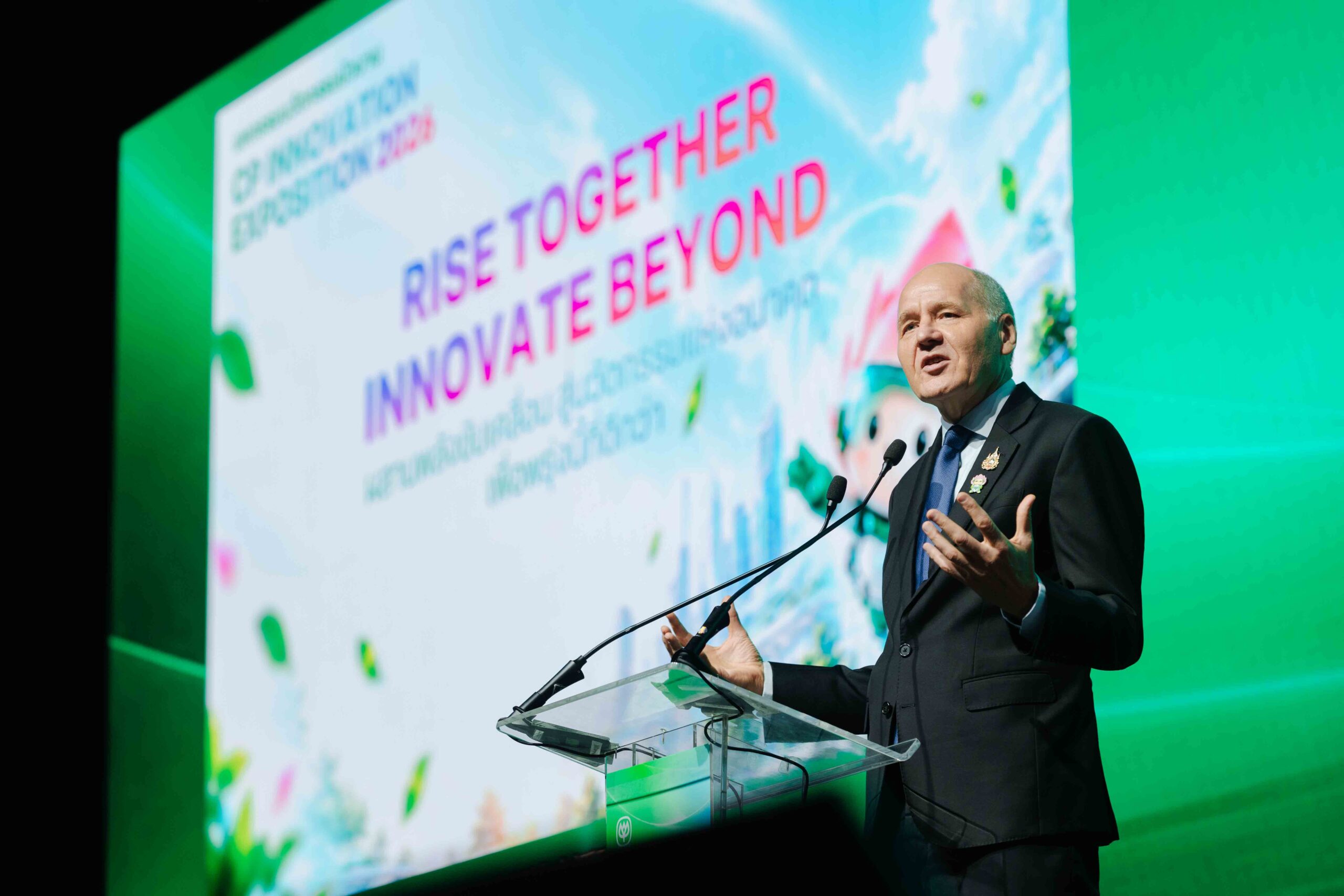 นายซิกเว่ เบรกเก้กล่าวบนเวทีข้างจอข้อความ Rise Together, Innovate Beyond