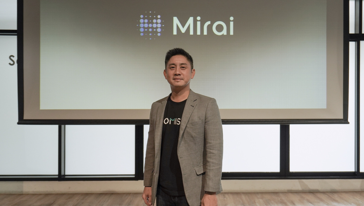 ปีเตอร์ พรประยุทธ ยืนหน้าโลโก้ Mirai ในงานเปิดตัว