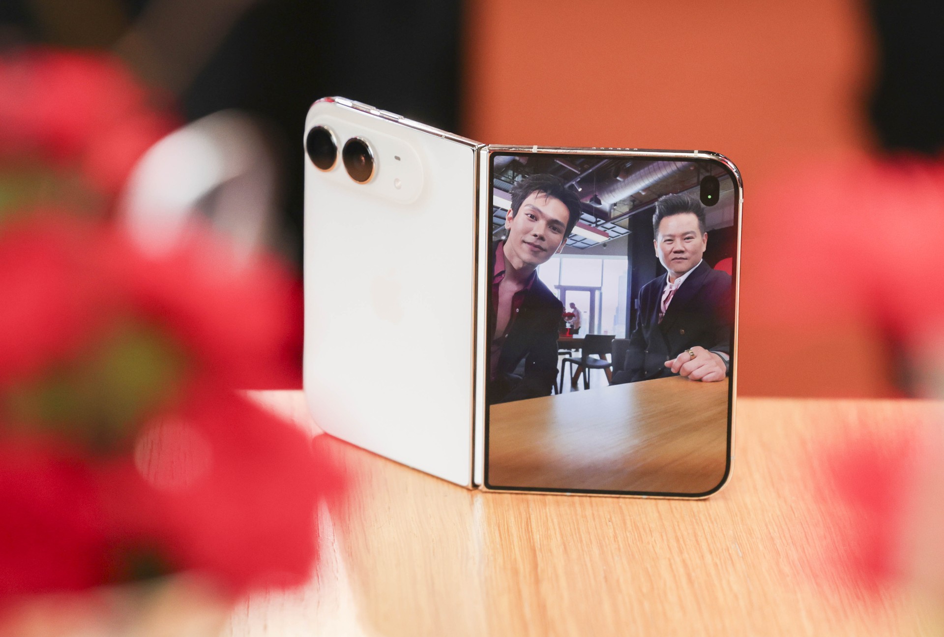 iPhone Duo วางบนแท่นไม้ โดยหน้าจอแสดงภาพผู้ร่วมงาน